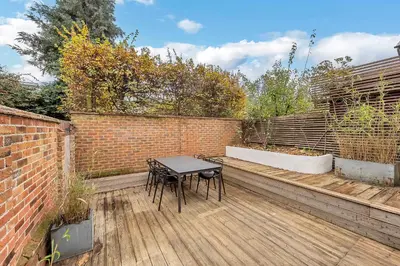 a patio with a table and a brick wall at 7D Albert St - sleeps 4 guests with parking on request in Bury Saint Edmunds