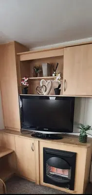 a entertainment center with a tv and a fireplace at Buxton's Holiday Home - Park Holiday's complex - Beach Access - Free WiFi in Saint Osyth