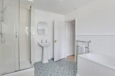 a white bathroom with a sink and a shower at Acorn Cottage at Finchingfield Holiday Cottages in Finchingfield