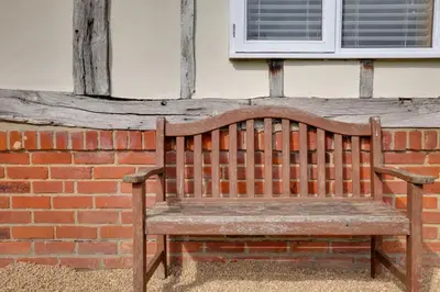 a wooden bench sitting in front of a brick wall at Acorn Cottage at Finchingfield Holiday Cottages in Finchingfield