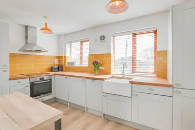 a kitchen with white cabinets and yellow tiles at Acorn Cottage at Finchingfield Holiday Cottages in Finchingfield