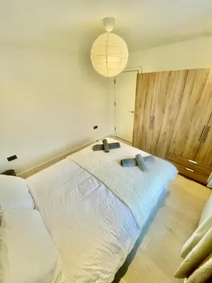 a bedroom with a large white bed with a light fixture at beautiful 3 bedroom apartment in cambridge sleeps 7 in Milton
