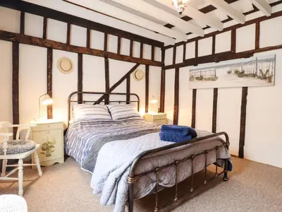 a bedroom with a bed in a room with striped walls at Driftwood Cottage in Harwich