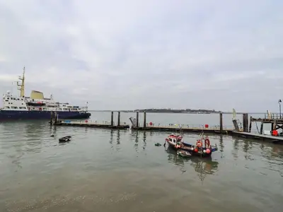 a boat in the water next to a dock at Driftwood Cottage in Harwich