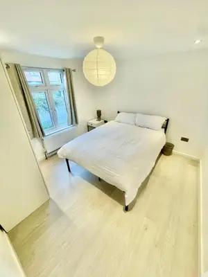 a bedroom with a white bed and a large window at Modern 2 bedroom apartment in cambridge in Milton