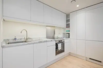 a kitchen with white cabinets and a sink at Stunning Central Apt With Parking in Cambridge