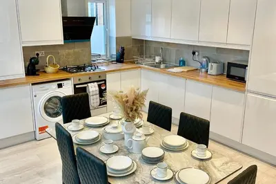 a kitchen with a dining table with chairs and a kitchen with a washing machine at 3 Bed Flat - Sleeps 6 - Parking - Wifi in Cambridge