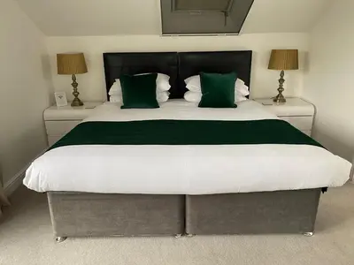 a bedroom with a large bed with green pillows at Tirah Guest House in Aldeburgh