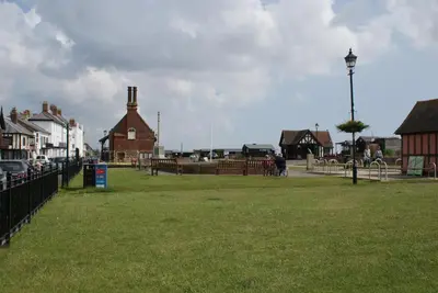 a park with a fence and houses and a street at Tirah Guest House in Aldeburgh