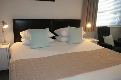a bedroom with a large bed with white pillows at Tirah Guest House in Aldeburgh