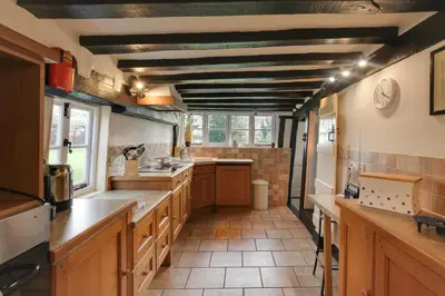 a large kitchen with wooden cabinets and a ceiling at Willow cottage in Saxtead