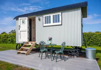 a tiny house with a table and chairs on a deck at The Shepherds Hut at Anvil House in Woodbridge