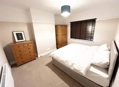 a bedroom with a bed and a dresser and a window at Leigh On Sea -Broadway-Two Bed with Garden in Southend-on-Sea