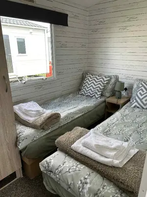 two beds in a room with a window at Adventure Van 6 berth St Osyth Beach Park in Saint Osyth