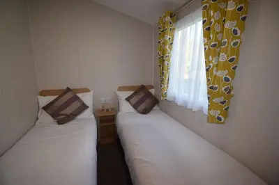 two twin beds in a room with a window at 25 Poplars Way Walton on Naze in Walton-on-the-Naze