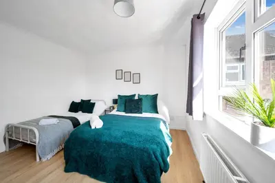 a white bedroom with two beds and a window at Chic Colchester Flat in Colchester
