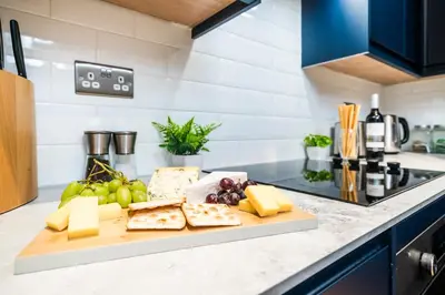 a cutting board with cheese and fruit on a kitchen counter at 2 Bed Elegant home with Parking in Harlow in Harlow