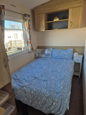 a small bedroom with a bed and a window at 3 Bedroom 2 Bathroom Caravan Charlie Delta in Saint Osyth