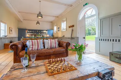 a living room with a couch and chessboard on a table at Belchamp Hall Stables in Belchamp Otten