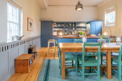 a kitchen with a wooden table and blue cabinets at Belchamp Hall Stables in Belchamp Otten