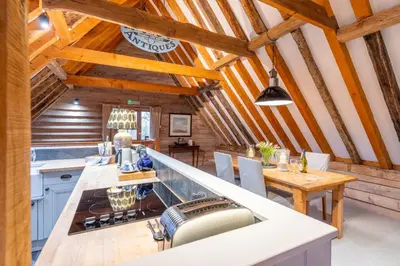 a kitchen with wooden ceilings and a table and chairs at Belchamp Hall Hayloft in Belchamp Otten
