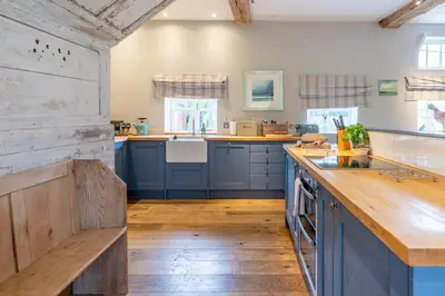 a kitchen with blue cabinets and a wooden counter top at Belchamp Hall Coach House in Belchamp Otten