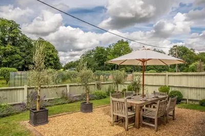 a wooden table with an umbrella in a garden at Belchamp Hall Coach House in Belchamp Otten