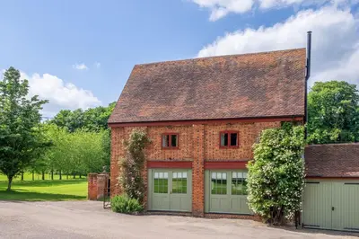 a red brick house with two garage doors at Belchamp Hall Coach House in Belchamp Otten