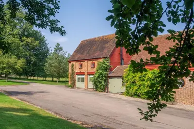 a red barn with a driveway in front of it at Belchamp Hall Coach House in Belchamp Otten