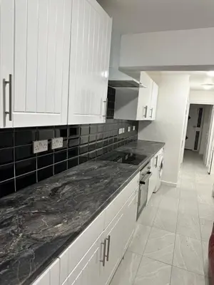 a kitchen with white cabinets and a black counter top at Basildon Everlight Villa in Basildon