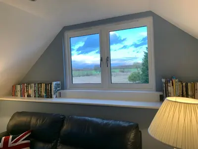 a living room with a window and a couch at Magog View in Sawston