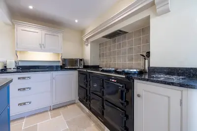 a kitchen with white cabinets and black appliances at The Cat House in Woolverstone
