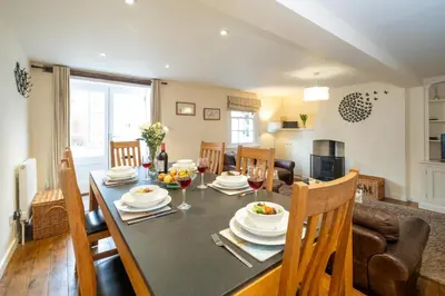 a dining room and living room with a table and chairs at Emeny Cottage - Aldeburgh Coastal Cottages in Aldeburgh