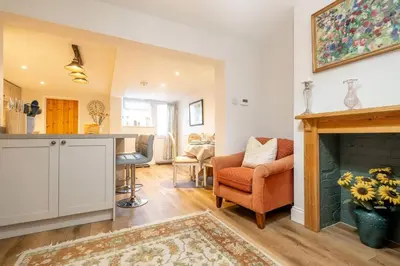 a living room with a fireplace and a table and chairs at 7 Prospect Place - Aldeburgh Coastal Cottages in Leiston