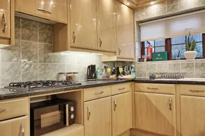 a kitchen with wooden cabinets and a stove top oven at Stylish 5-Bed London Residence Featuring Garden, Parking & High-Speed Internet in Nevendon