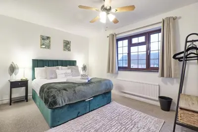 a bedroom with a bed and a ceiling fan at Stylish 5-Bed London Residence Featuring Garden, Parking & High-Speed Internet in Nevendon