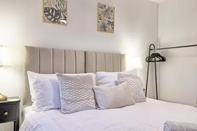 a bedroom with a white bed with white pillows at Stylish 5-Bed London Residence Featuring Garden, Parking & High-Speed Internet in Nevendon