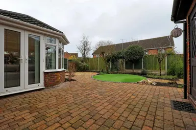 a patio with a green lawn in front of a house at Stylish 5-Bed London Residence Featuring Garden, Parking & High-Speed Internet in Nevendon