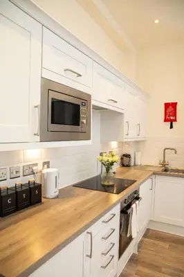 a kitchen with white cabinets and a microwave at Seaview Apartments - 30 Marine Parade, Harwich - Perfect for business & long term stays in Harwich