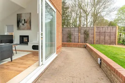 a patio with a sliding glass door and a lawn at Luxury self contained one bedroom - Sawbridgeworth in Sheering