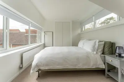 a white bedroom with a large bed and windows at Luxury self contained one bedroom - Sawbridgeworth in Sheering