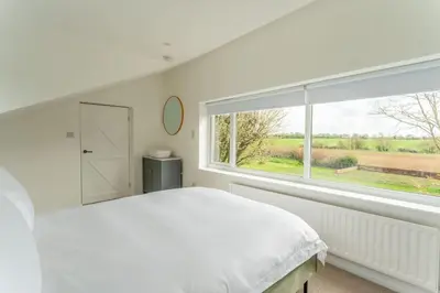 a bedroom with a white bed and a large window at Luxury self contained one bedroom - Sawbridgeworth in Sheering