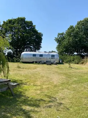 a silver trailer parked in a field with trees at Bury - Lodge - Sleeps 2 - Parking in Great Welnetham