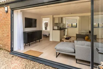 a living room with a couch and a tv at Modern self contained one bedroom with garden in Sheering