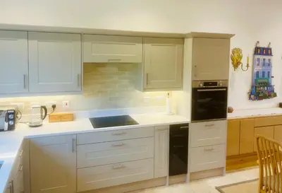 a kitchen with white cabinets and a black refrigerator at North Farm fits 1-6 people in Sawston