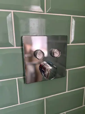 a green tiled bathroom wall with a mirror and aaucet at Crown Lodge, Great Glemham in Saxmundham