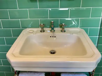 a white sink in a bathroom with green tiles at Crown Lodge, Great Glemham in Saxmundham