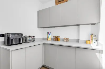 a white kitchen with white cabinets and a microwave at House of Hertfordshire in Datchworth