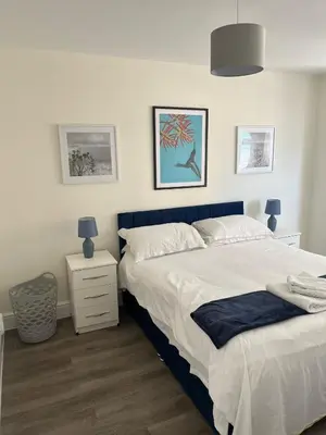 a bedroom with a large bed with a blue headboard at Seaview House with Sea View Brand New- 3 Bedrooms - Harwich, Dovercourt in Lancing