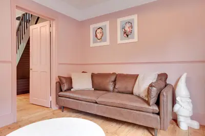 a living room with a brown couch and a staircase at Luxury Two Bedroom Cottage - Bishops Stortford in Bishops Stortford